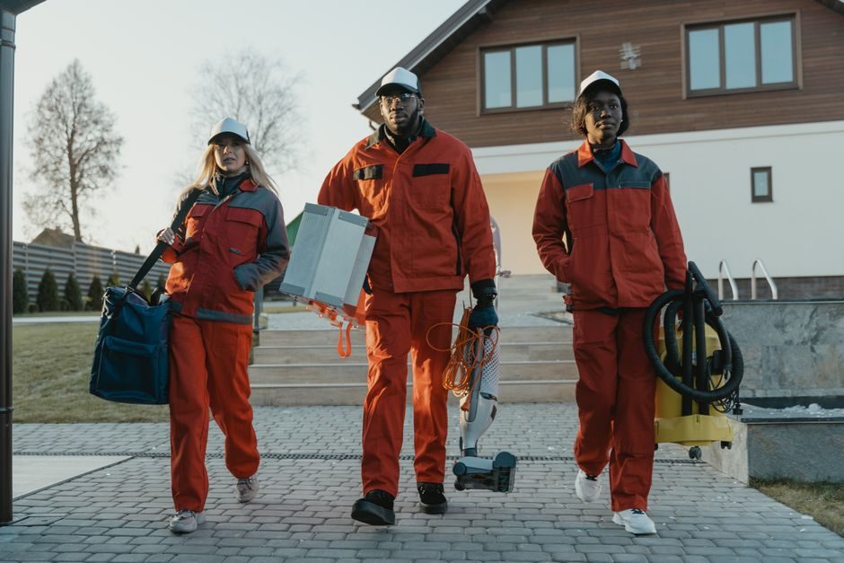 Trois agents de nettoyage en tenue de travail arrivant sur un site avec leur matériel