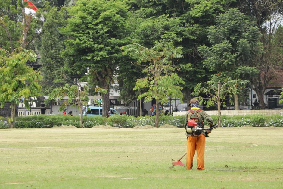 Agent d'entretien d'espaces verts coupant l'herbe d'un grand parc à la débroussailleuse